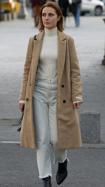 Customer wearing camel wool overcoat walking through park in autumn